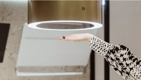 Osoba testująca okap kuchenny gestem ręki.