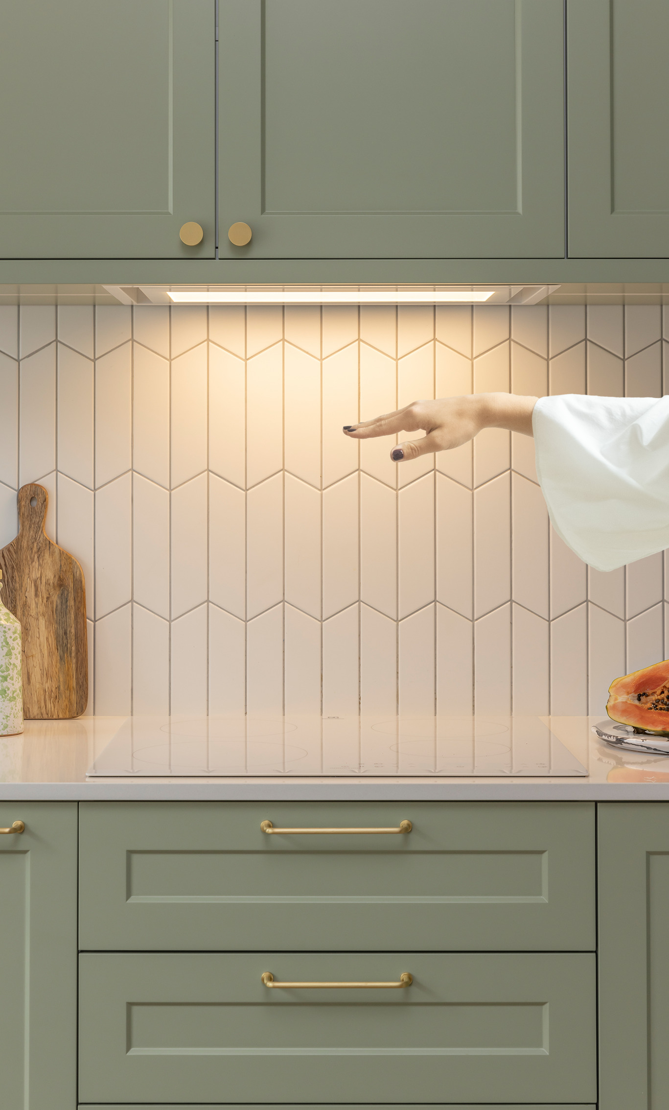 Ręka wskazująca na okap kuchenny pod szafką.